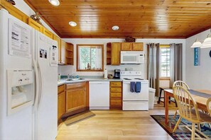 Une cuisine de taille réduite, dotée de meubles en bois, d’un réfrigérateur blanc, d’un four à micro-ondes et d’une cuisinière.