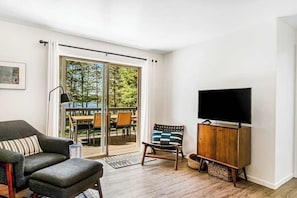 A modern living room with a sofa, a television, and a sliding glass door leading to an outdoor patio.