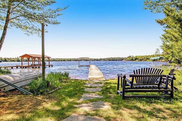 A lakeside view with a wooden dock, a gazebo, and a bench.