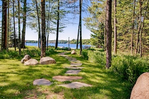 A forested area with a stone path leading to a body of water.