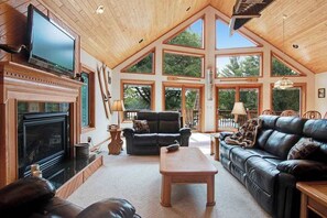 Ein geräumiges Wohnzimmer mit Kamin, Ledersofas und großen Fenstern.