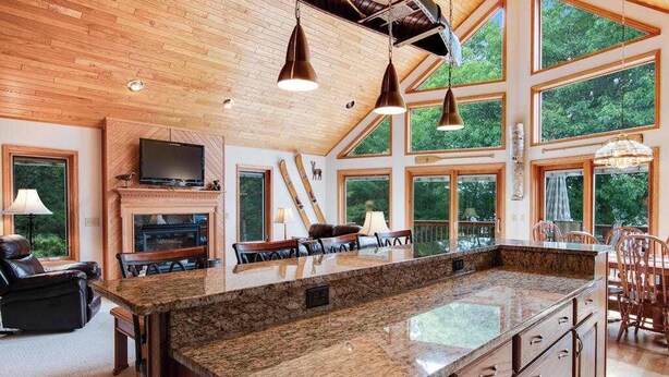 A spacious kitchen with a large island, wooden ceiling, and large windows. - Dog-friendly lakefront getaway with dock, firepit, wet bar, game room, & AC (Eagle River)