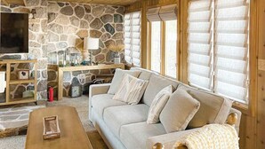 Ein gemütliches Wohnzimmer mit Steinwand, einer Couch, einem Couchtisch und einem Fernseher.