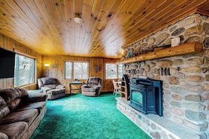 Hirsihutun sisustus: kivitakka, puuseinät ja vihreä matto.