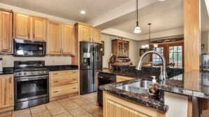 Una cocina con armarios de madera, electrodomésticos de acero inoxidable, encimera de granito y una isla grande con un lavamanos.