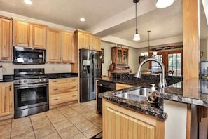 Una cocina con armarios de madera, electrodomésticos de acero inoxidable, encimera de granito y una isla grande con un lavamanos.