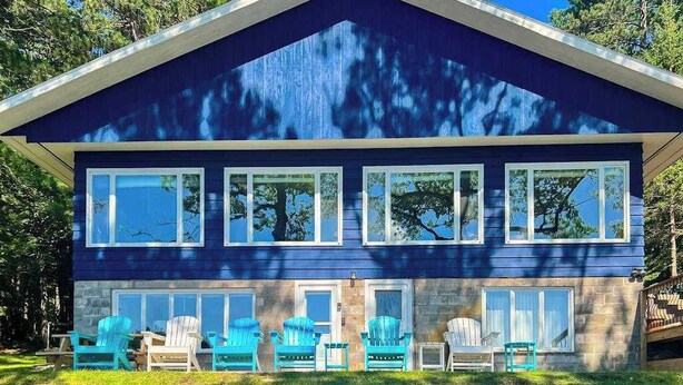 Et toetagers hus med en skarp tagspær, store vinduer og en veranda med udendørs siddepladser.