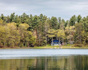 Un chalet au bord du lac, doté d’un quai, et entouré d’une forêt dense.