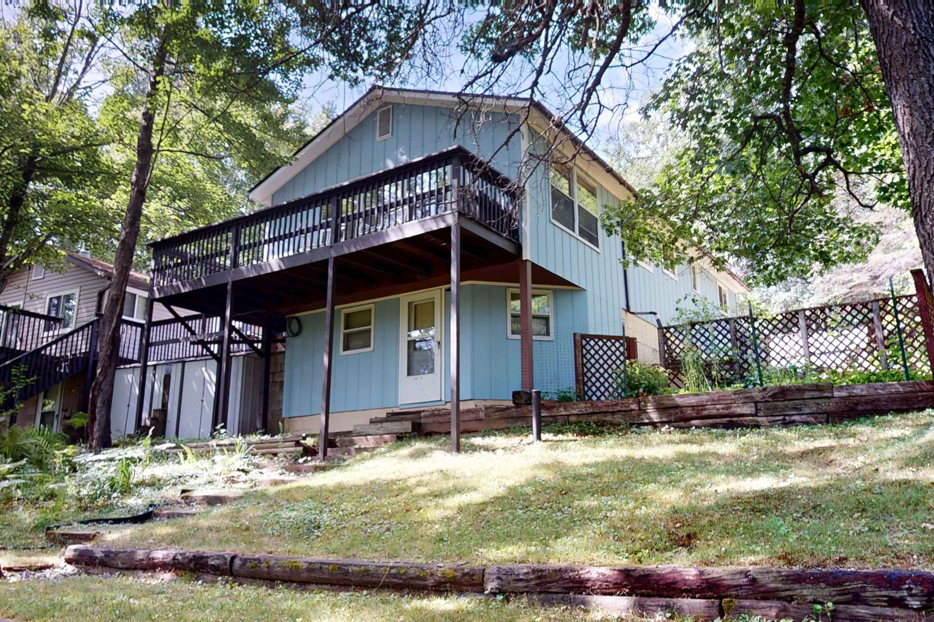 A two-story house with a porch, a small front yard, and a wooden fence.