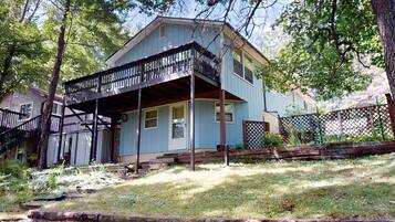 A two-story house with a porch, a small front yard, and a wooden fence.