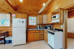 A wooden cabin-style kitchen with a refrigerator, stove, microwave, and wooden cabinets. - Cozy cabins w/ fireplace, whirlpool tub, access to private dock, & fire pit (Mercer)
