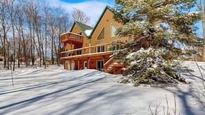 A log cabin with a balcony, surrounded by snow-covered ground and trees. - Cozy Retreat, perfect for outdoor enthusiasts, near lakes, trails & downtown (Phelps)