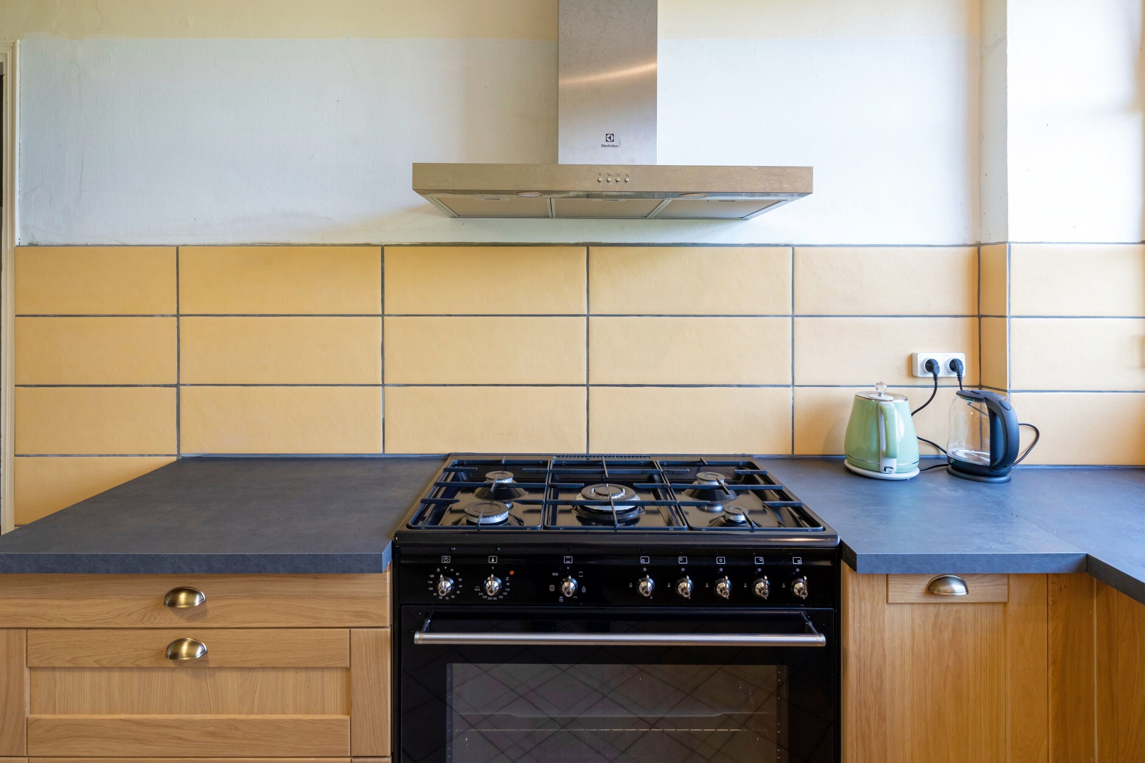 Una cocina con estufa, horno y hervidor sobre la encimera.