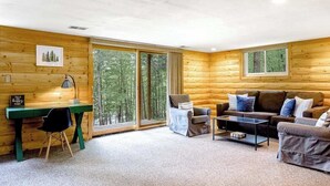 Ein Holzinterieur mit Schreibtisch, zwei Stühlen, einer Couch und einem Couchtisch.