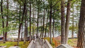 Una escalera de madera que conduce a un muelle, rodeada de árboles altos y un lago.