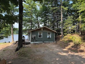 A cabin with a dock, surrounded by trees and a lake.
