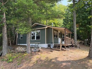 A cabin with a porch, surrounded by trees.