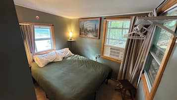 Une chambre à coucher avec un lit, une lampe de chevet, une fenêtre avec des rideaux et un tableau au mur.