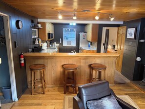 A kitchen with wooden bar stools, a refrigerator, and a microwave. - Blue Jay Cabin | Lakefront cabin in Rhinelander with dock & row boat (Rhinelander)