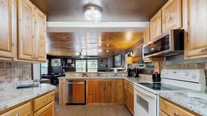 A kitchen with wooden cabinets, a granite countertop, a built-in oven, and a microwave. - Blue Jay Cabin | Lakefront cabin in Rhinelander with dock & row boat (Rhinelander)