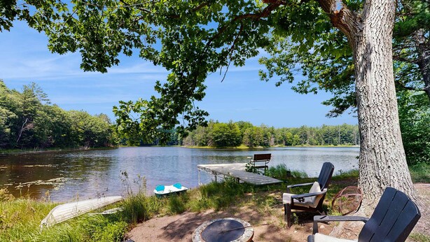 A lakeside setting with a dock, chairs, and a fire pit. - Blue Jay Cabin | Lakefront cabin in Rhinelander with dock & row boat (Rhinelander)