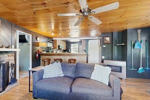 A cozy living room with a gray sectional sofa, a ceiling fan, and a fireplace.