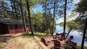 Une cabane avec un quai qui s’avance sur un lac, entourée d’arbres.