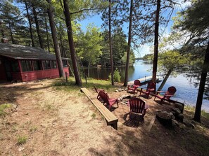 A cabin with a dock extending into a lake, surrounded by trees.