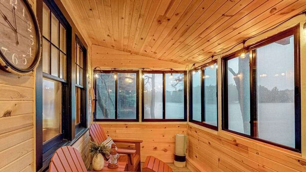 L’intérieur d’un chalet en bois, avec une grande horloge, des murs en bois et de grandes fenêtres.