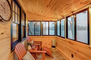 Interior d'una cabana de fusta amb un rellotge gran, parets de fusta i grans finestres.