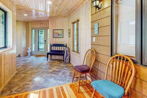 Un interior de madera con un banco, sillas y una alfombra.