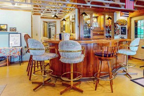 Una zona de bar con taburetes de madera, una barra y una lámpara colgante.