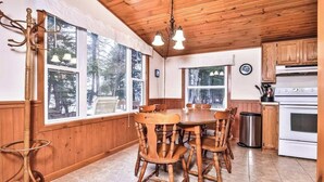 Una cocina con paneles de madera, una mesa y sillas, ventanas amplias y una estufa.
