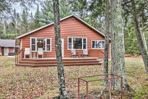 Une cabane dotée d’une terrasse, entourée d’arbres.