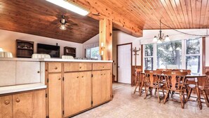 Interior de madera con isla de cocina, mesa de comedor, sillas y ventilador de techo.