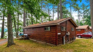 En stuga av trä med ett sluttande tak, en liten veranda och en synlig vattenkran.