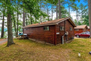 A wooden cabin with a sloped roof, a small porch, and a visible water spigot. - Snowy lake-view cabin with fireplace, full kitchen, TV, dock, & DVD player (St. Germain)
