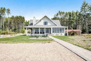 A large house with a covered porch, a paved driveway, and a lawn. - Dog-friendly, lakefront house with beach access, dock, AC, W/D, patio, & firepit (St. Germain)