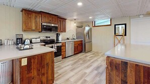 Una cocina con armarios de madera, electrodomésticos de acero inoxidable y techo blanco.