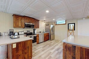 Una cocina con armarios de madera, electrodomésticos de acero inoxidable y techo blanco.