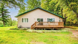 Ein eingeschossiges Haus mit Veranda, umgeben von einem Rasen und Bäumen.