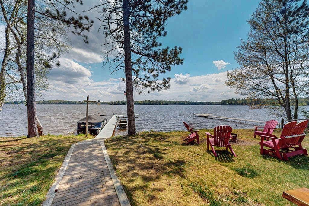 Une terrasse au bord du lac, avec des fauteuils Adirondack, un hamac et une jetée qui s’avance dans l’eau.