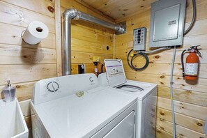 Ein Waschbereich mit Waschmaschine, Feuerlöscher und Bedienfeld.
