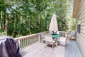 Une terrasse en bois avec des meubles d’extérieur, notamment une table et des chaises, ainsi qu’un barbecue.
