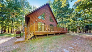 A cabin with a wooden exterior, a porch, and a stone pathway leading to it. - Rustic resort cabin with lake views, deck & access to docks, canoe, paddle boats (Mercer)