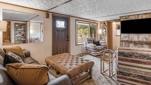 Ein Wohnzimmer mit einer Couch, einem Hocker und einem gemusterten Teppich.