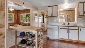 Eine moderne Küche mit Holzausstattung, einem integrierten Geschirrspüler und einem Holztisch mit Kochgeschirr.