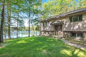 A house with a stone foundation, a front door, and a view of a lake. - Fantastic waterfront abode with wraparound deck, dock, & WiFi - dog-friendly (Manitowish Waters)
