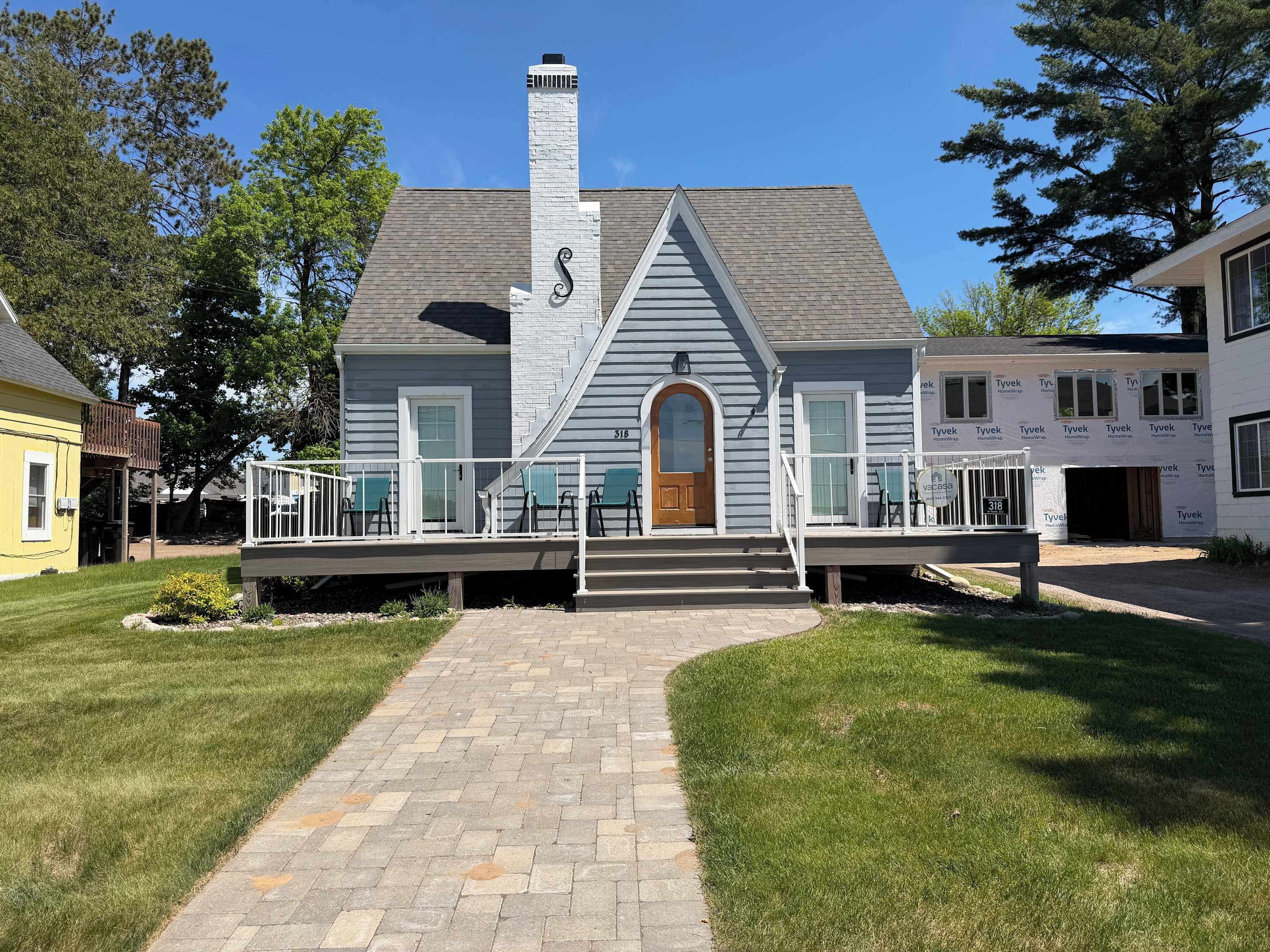 A two-story house with a front porch, a chimney, and a small deck.