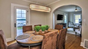 A dining area with a round table, chairs, and a hanging light fixture.